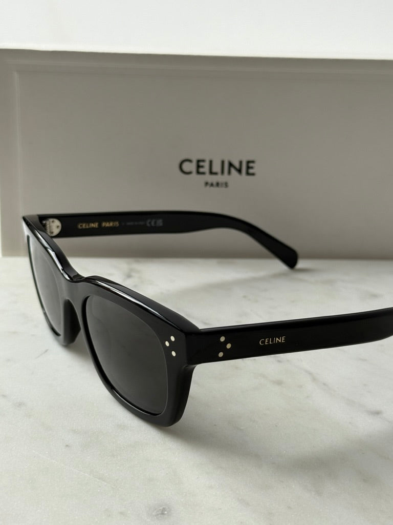 Black unisex sunglasses with dark lenses, front-left angle and logo detail