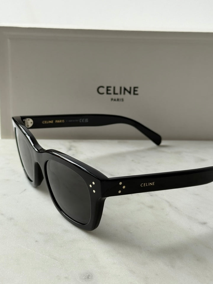 Black unisex sunglasses with dark lenses, front-left angle and logo detail