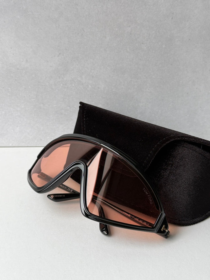 Black sunglasses with orange-tinted lenses and angular wrap frame, with case
