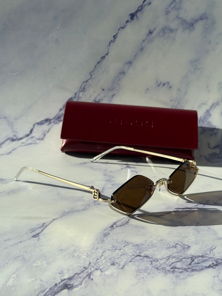 Gucci half-rim sunglasses with brown lenses and red case, angled view