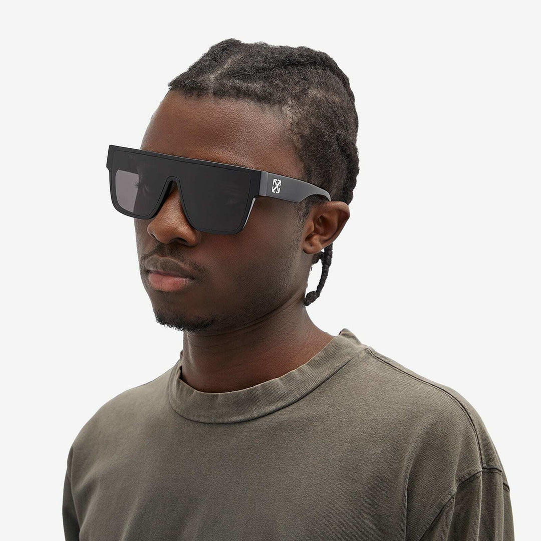 Black square sunglasses on a person, dark lenses and brand logo on temple