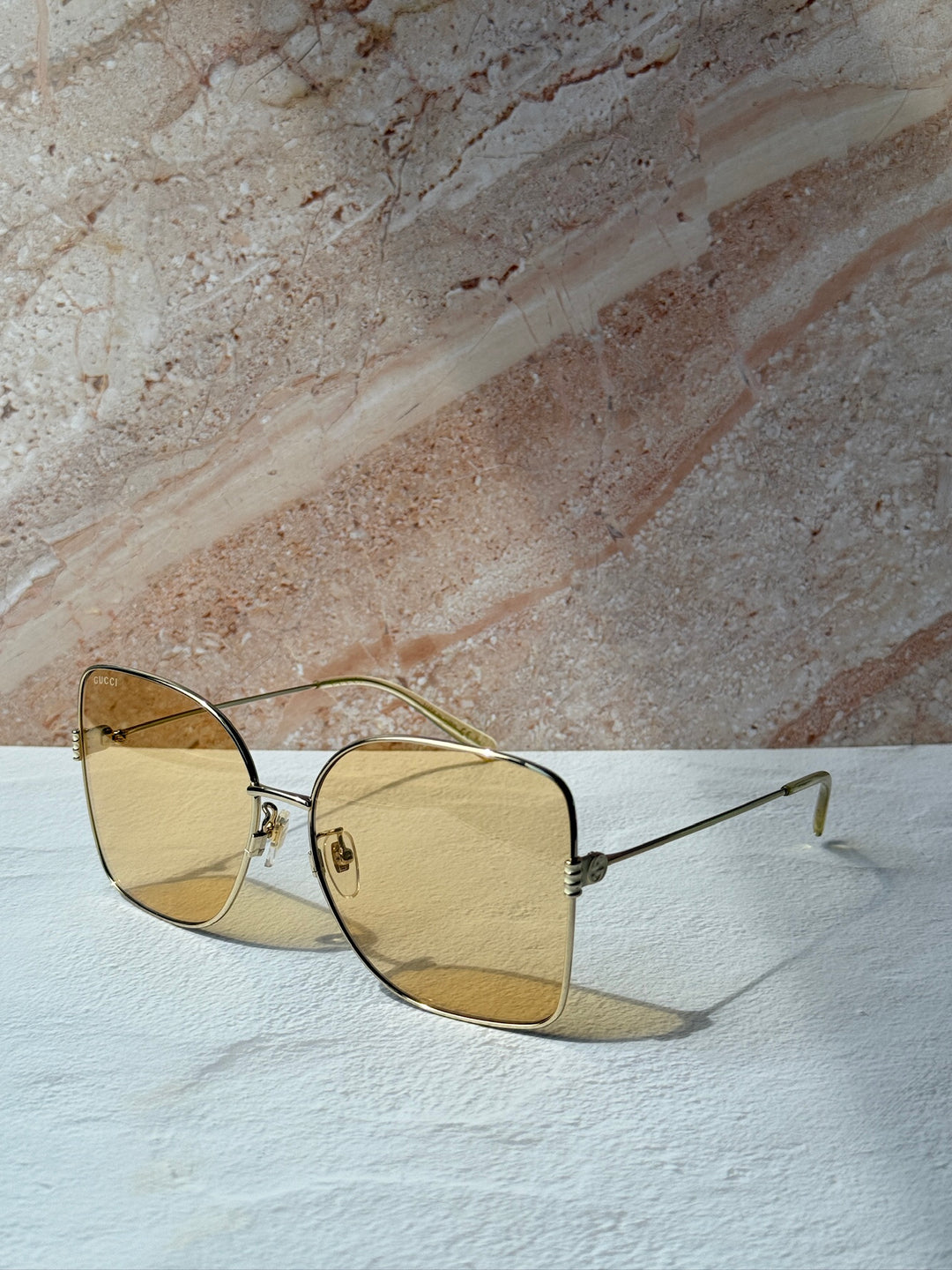 Gucci gold-tone square sunglasses with amber tinted lenses, angled side view