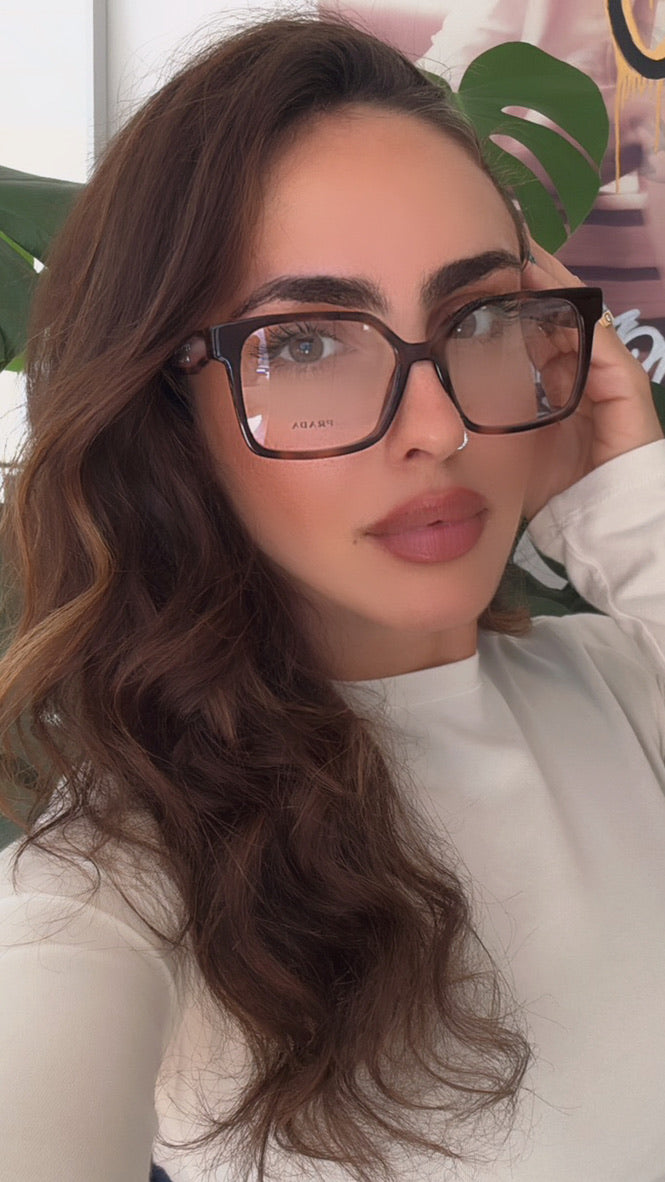 Woman wearing Prada mauve tortoise square eyeglass frames with dark temples
