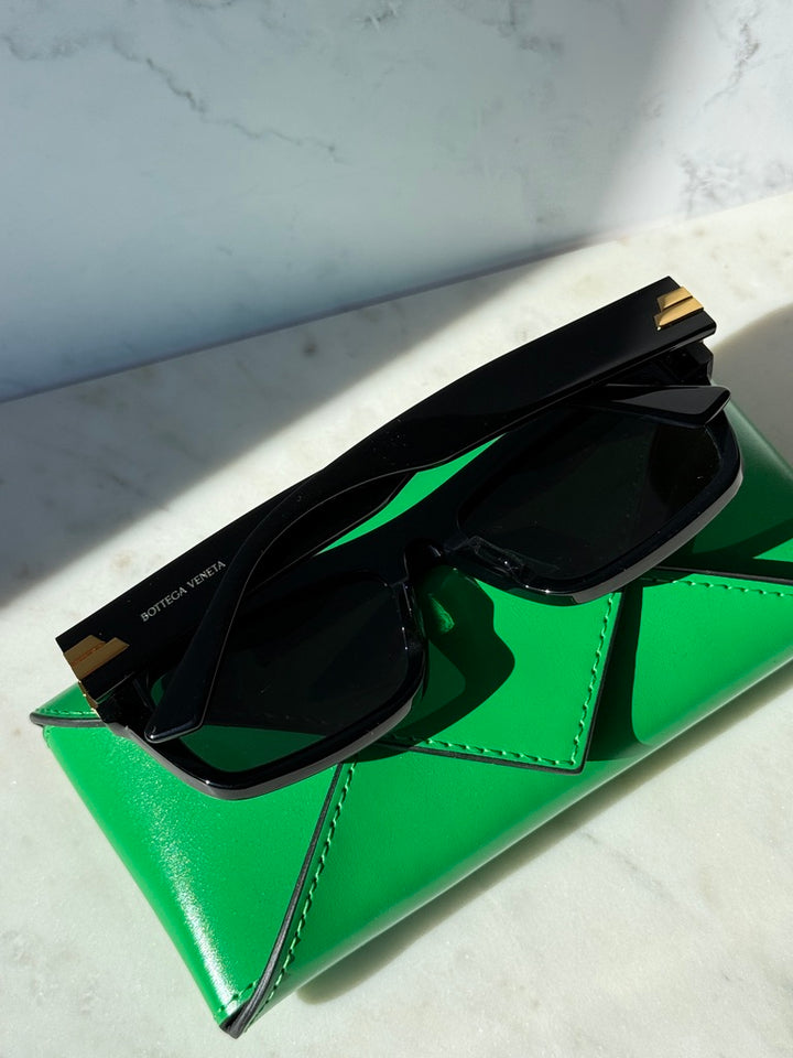 Black rectangular sunglasses with dark lenses and gold temple details, side angle