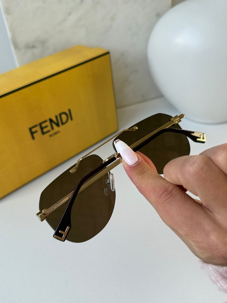 Gold aviator sunglasses close-up showing brown lenses and Fendi FF logo on temple