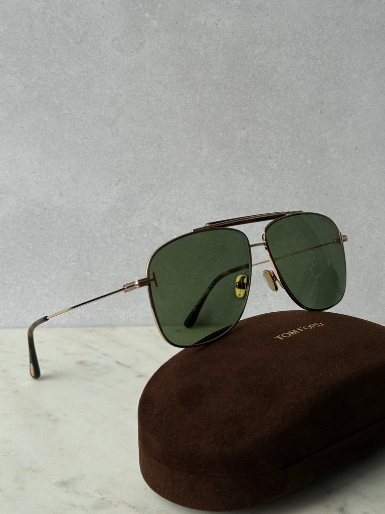 Green lens sunglasses with rose gold frames, side view on brown case
