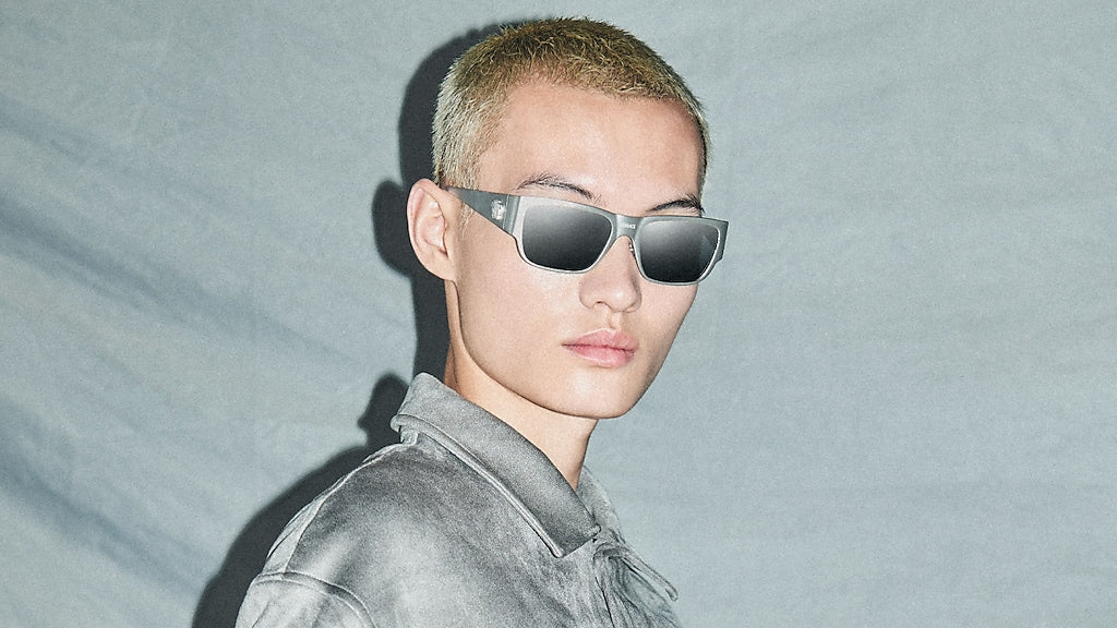 Versace silver sunglasses with dark lenses on a model, square frame with logo temples