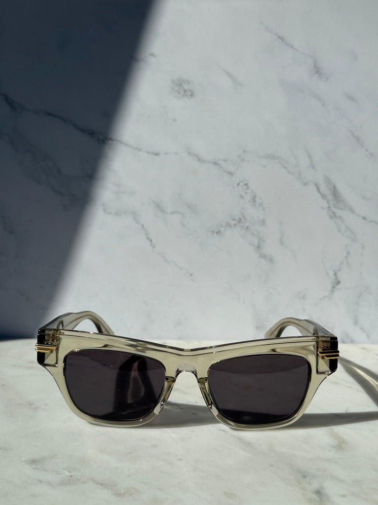 Mitre rectangular sunglasses with clear frame, dark lenses, and gold corner accents