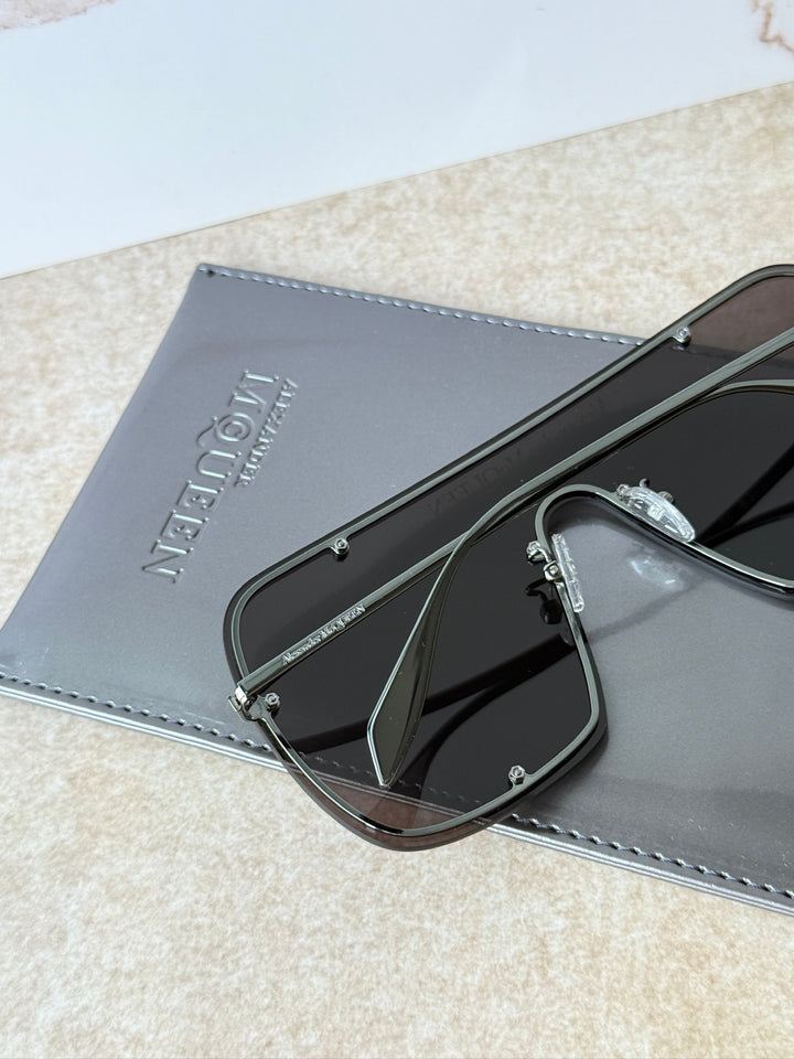 Close-up of oversized black studded mask sunglasses with dark lenses and metal hinges