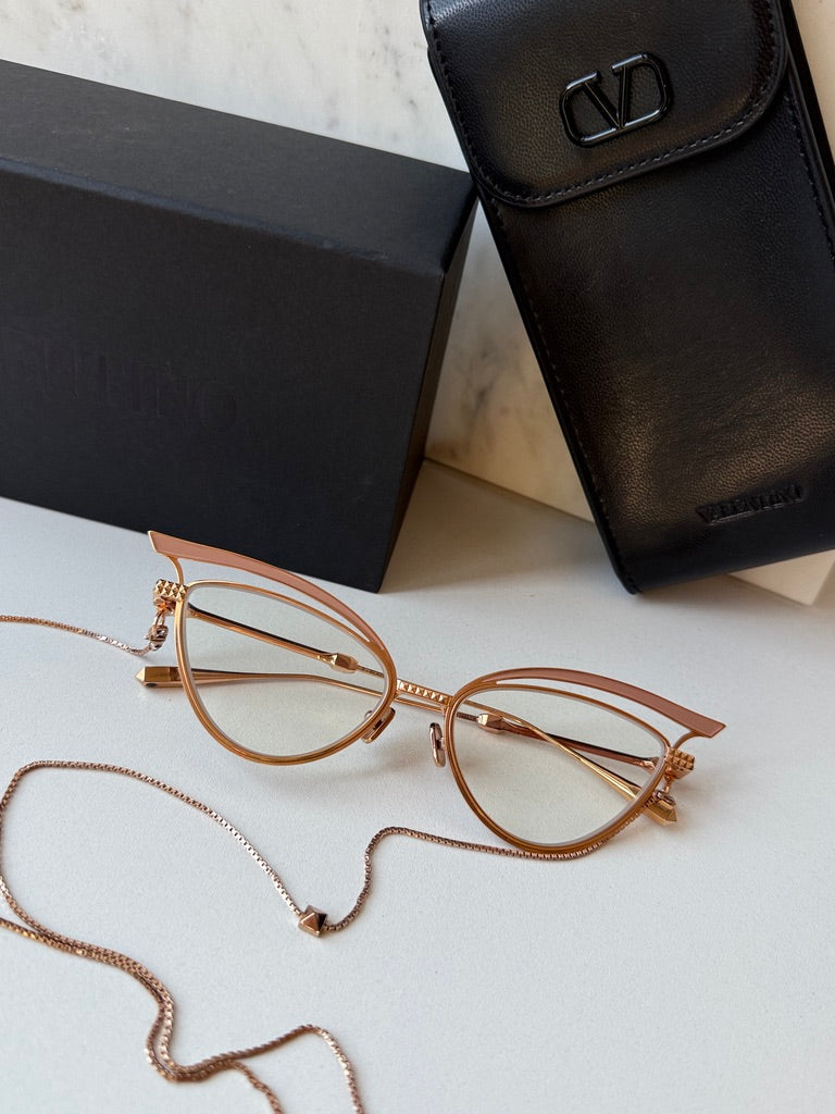 Pair of gold-tone cat-eye eyeglass frames with beige lenses and chain strap