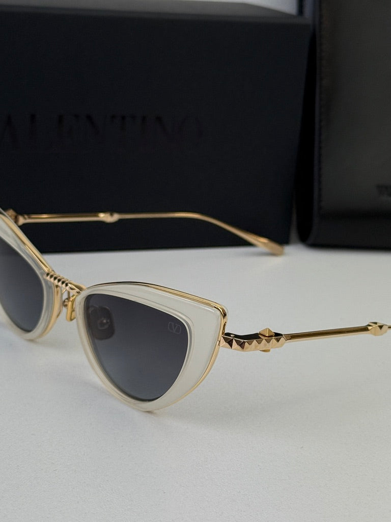 Close-up of white cat-eye sunglasses with gold-tone hinge and dark gray lenses