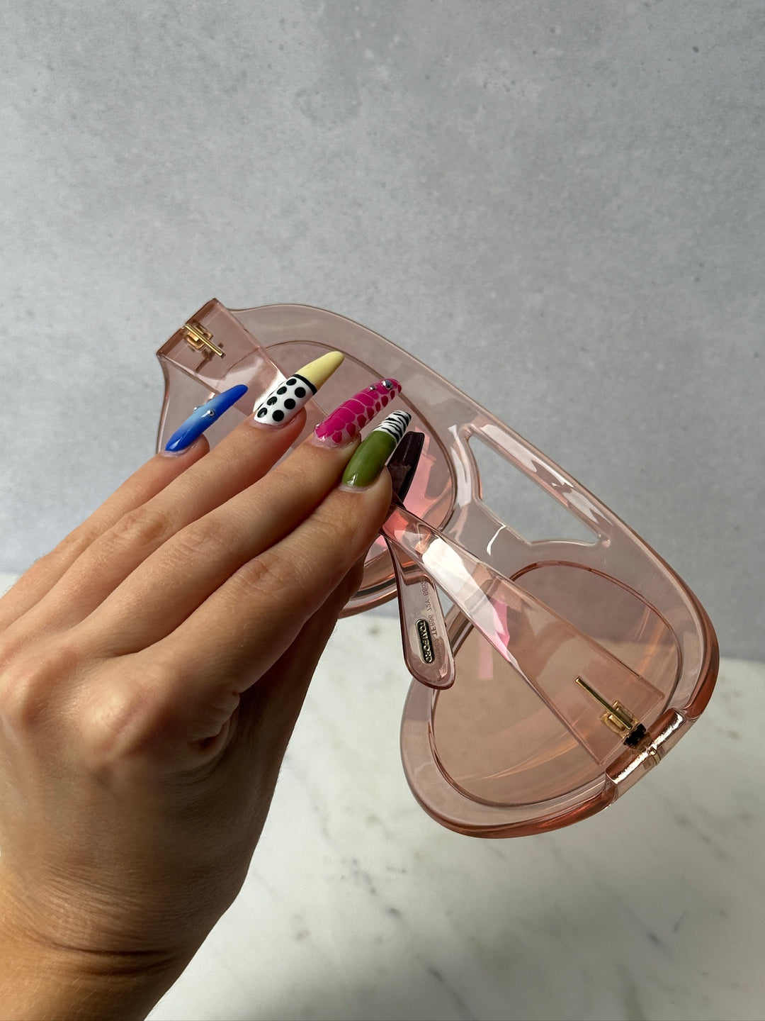 Pink oversized mask sunglasses with tinted lenses and gold-tone hinges, held open