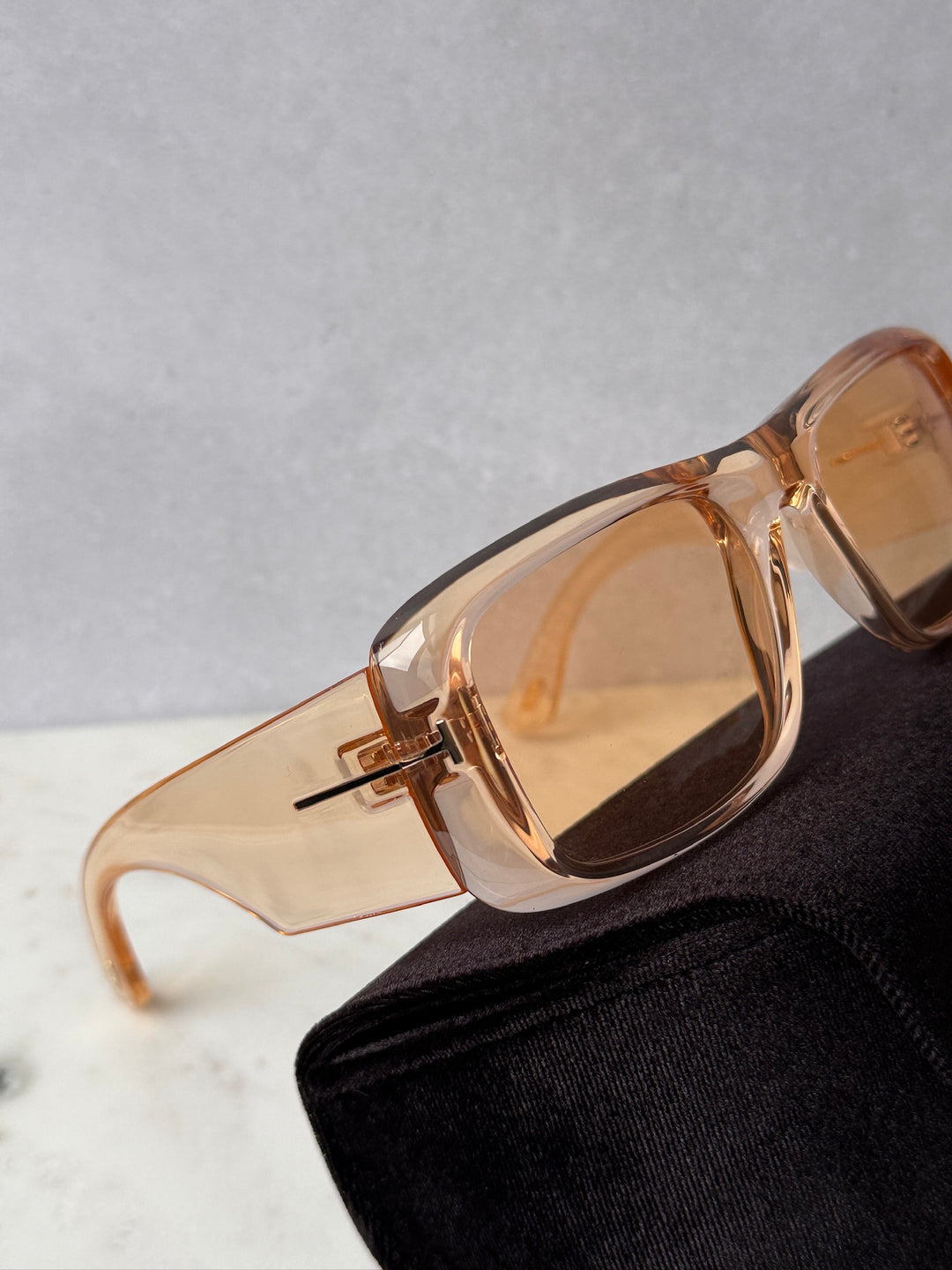Transparent orange sunglasses with amber tinted lenses, close view with black case