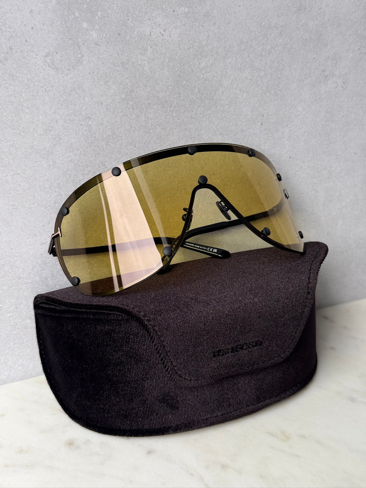 Yellow studded mask sunglasses with striped lenses on black protective pouch