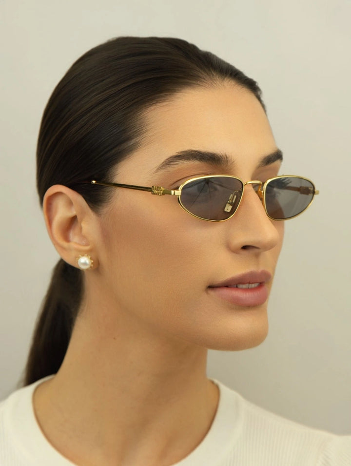 Gold oval sunglasses with grey lenses and brown-tinted temple tips, side view
