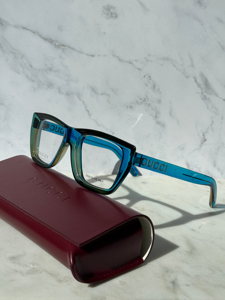Blue Gucci eyeglasses frames with rectangular clear lenses, teal temple accents.