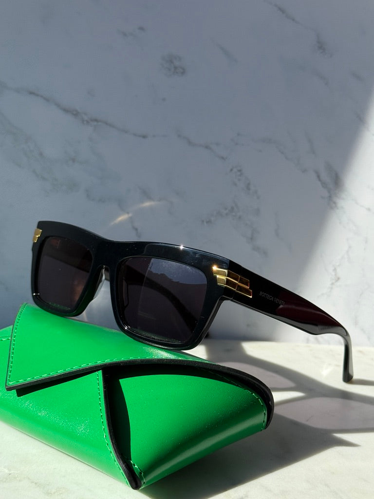 Black rectangular sunglasses with dark lenses and gold accent on temples