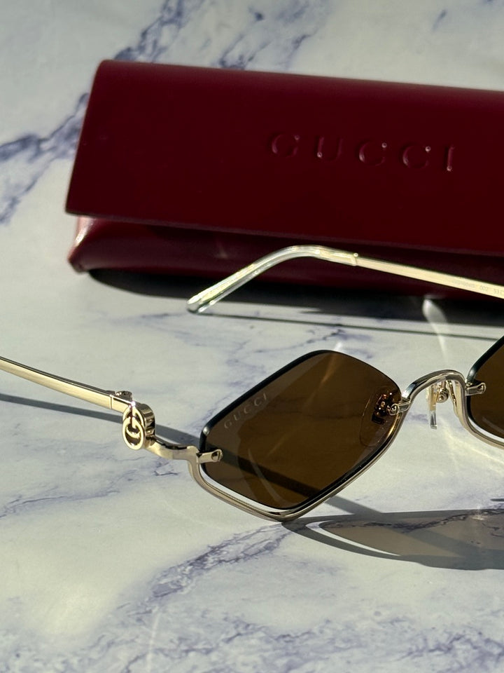 Gucci half-rim sunglasses with gold frame and brown lenses, close-up