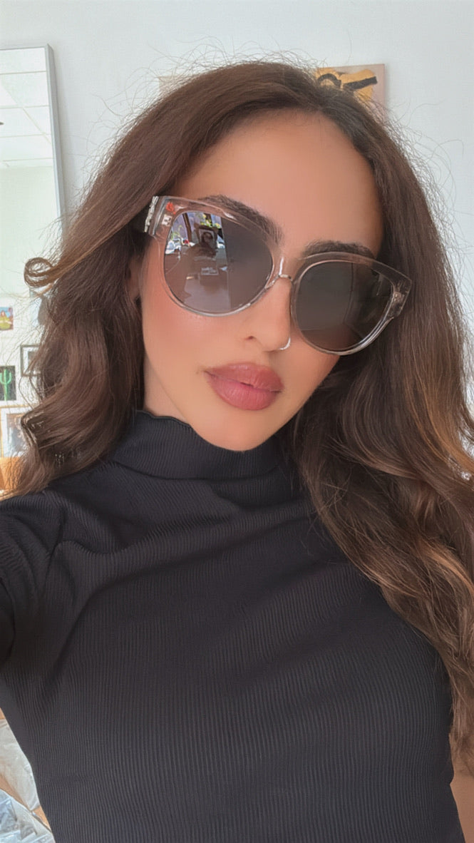 Woman wearing clear silver cat-eye sunglasses with dark lenses