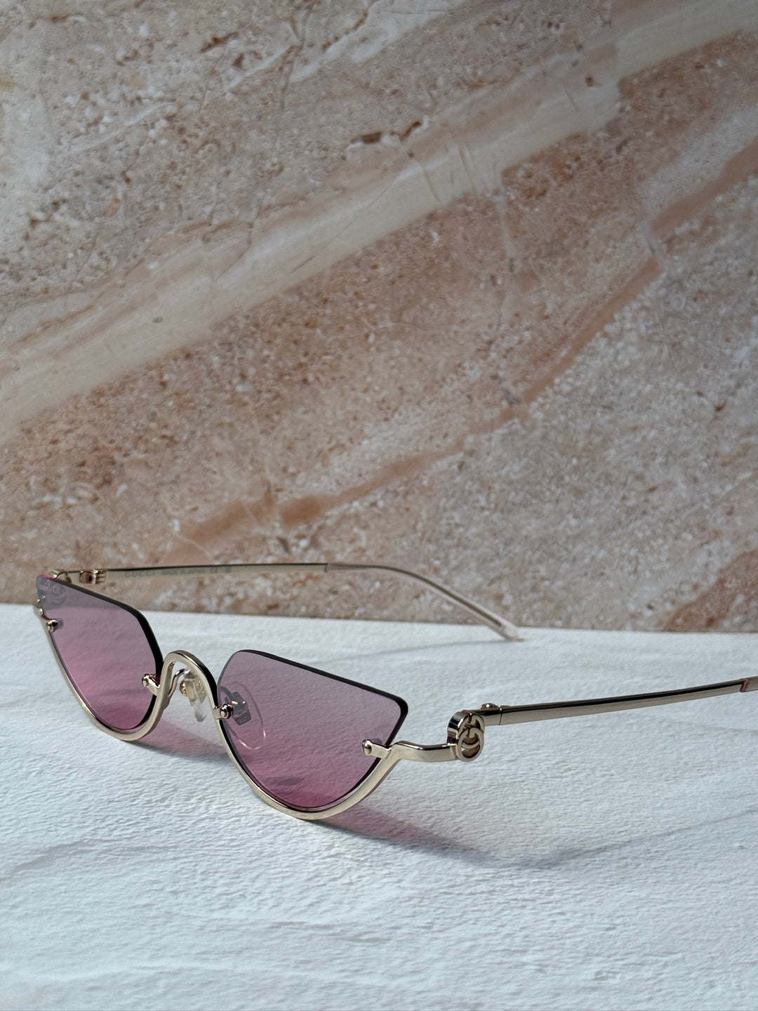 Gucci half-rim sunglasses angled view, gold frame with pink tinted lenses