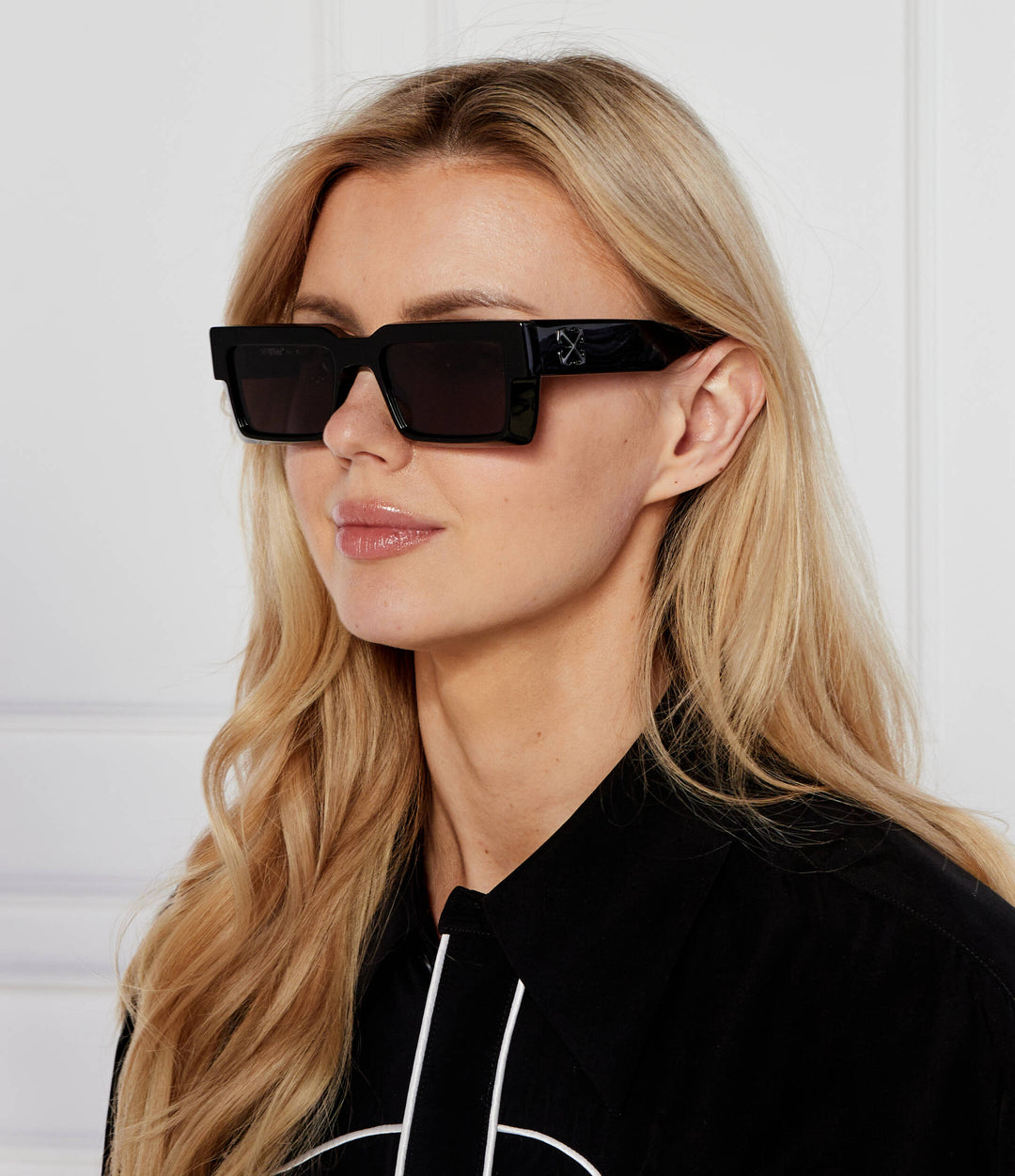 Woman wearing black rectangular sunglasses with dark lenses