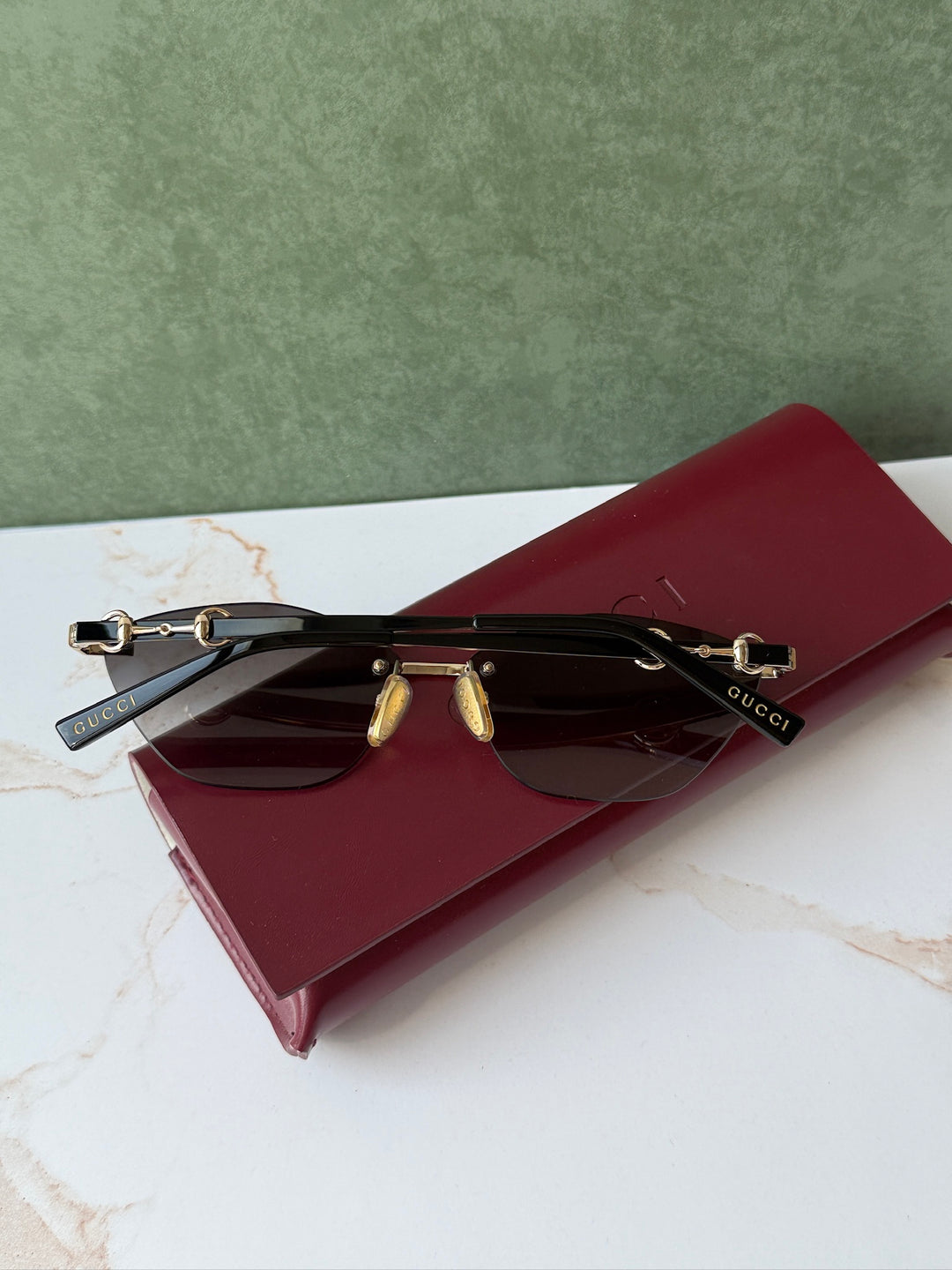 Gucci cat-eye sunglasses with gold frame, dark lenses, and horsebit bridge, side view