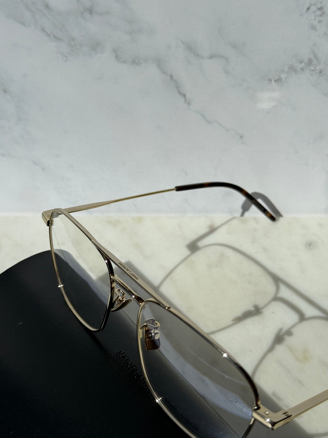 Gold aviator eyeglass frames with clear lenses and detailed metal hinge arms.