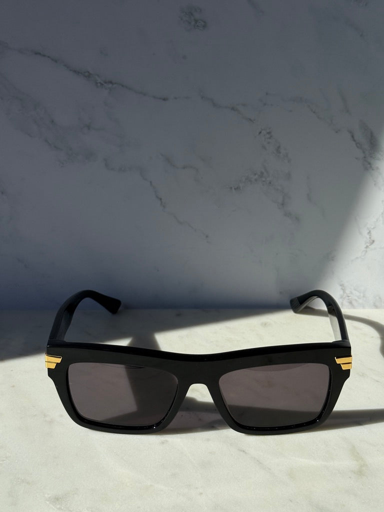 Black rectangular sunglasses with dark lenses and gold-striped temple tips