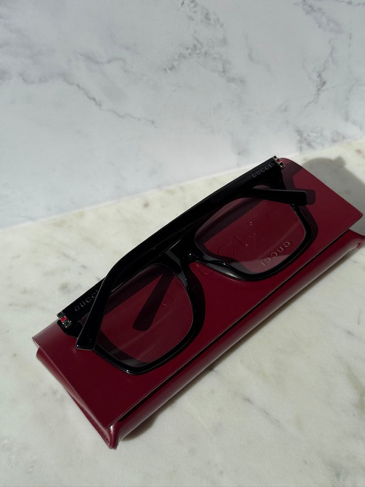 Black eyeglass frames with rectangular front and Gucci logo, angled side view
