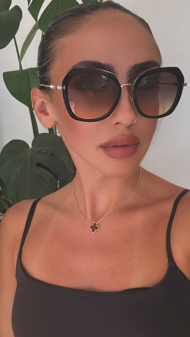 Tom Ford black and gold sunglasses on model, oversized square lenses with dark tint