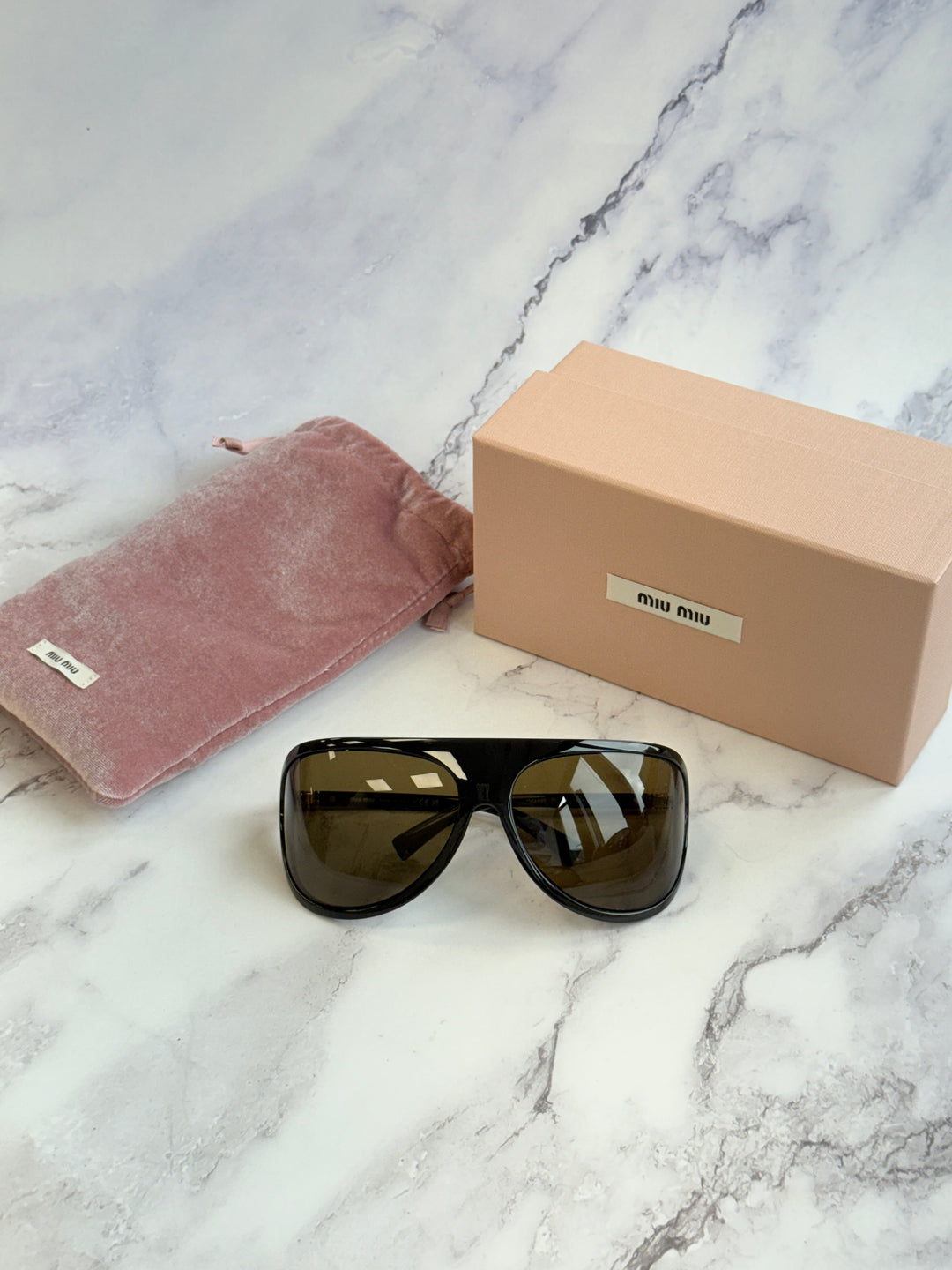 Shield sunglasses with black frames, brown lenses, and gold-tone hinge details.