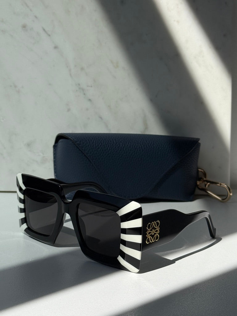 Loewe square sunglasses with black frames and white striped temples, gold emblem