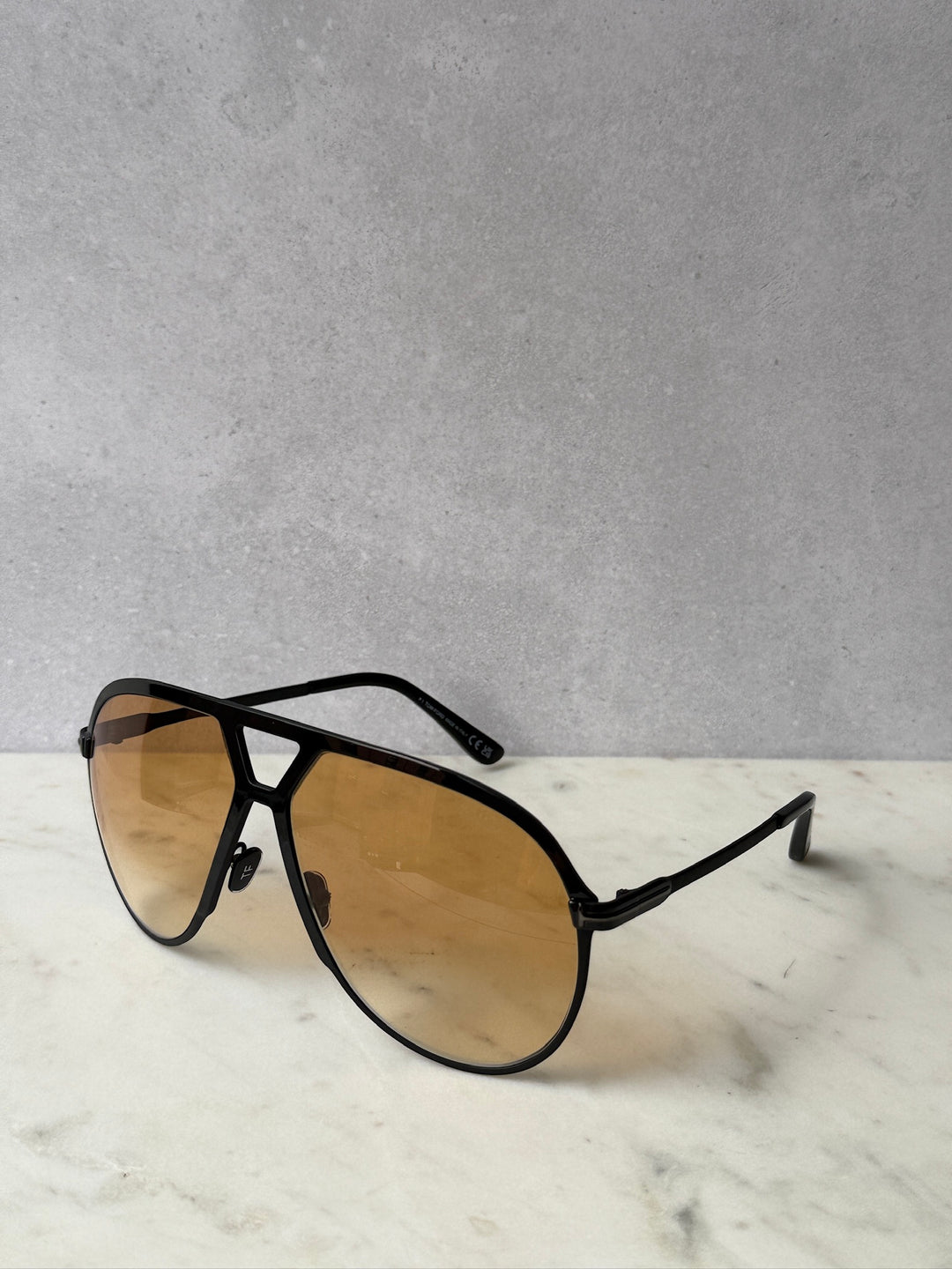 Oversized black aviator sunglasses with amber gradient lenses and angled temple tips