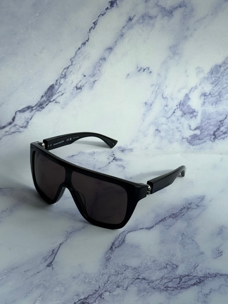 Black skull sunglasses with dark tinted lenses, resting on marble surface