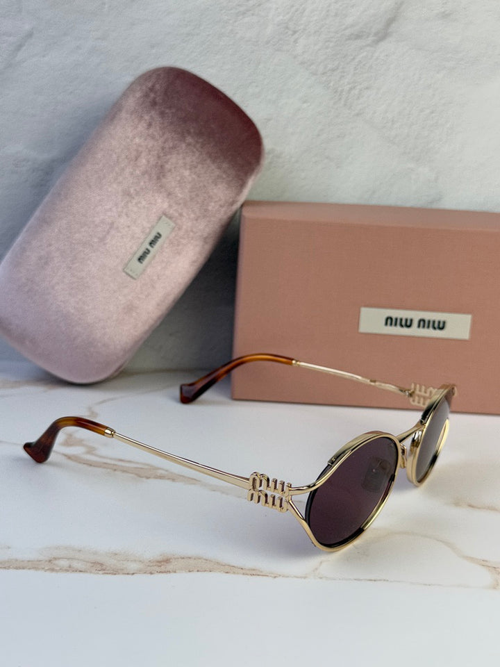 Miu Miu gold oval sunglasses with violet lenses, angled side view with case and box.