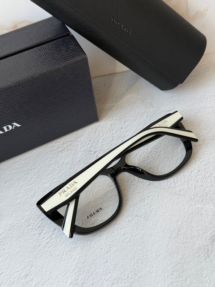 Black cat-eye eyeglasses frames with white inner temple panel and metal logo.