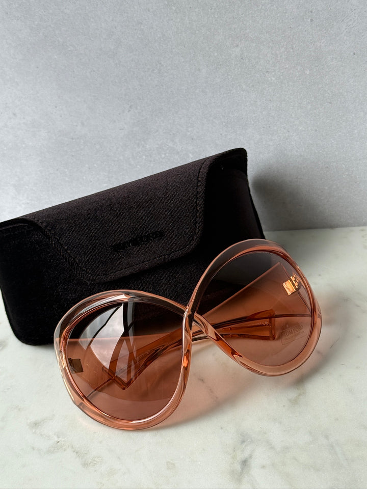 Oversized mask sunglasses with pink frame and brown lenses, in black zip pouch.