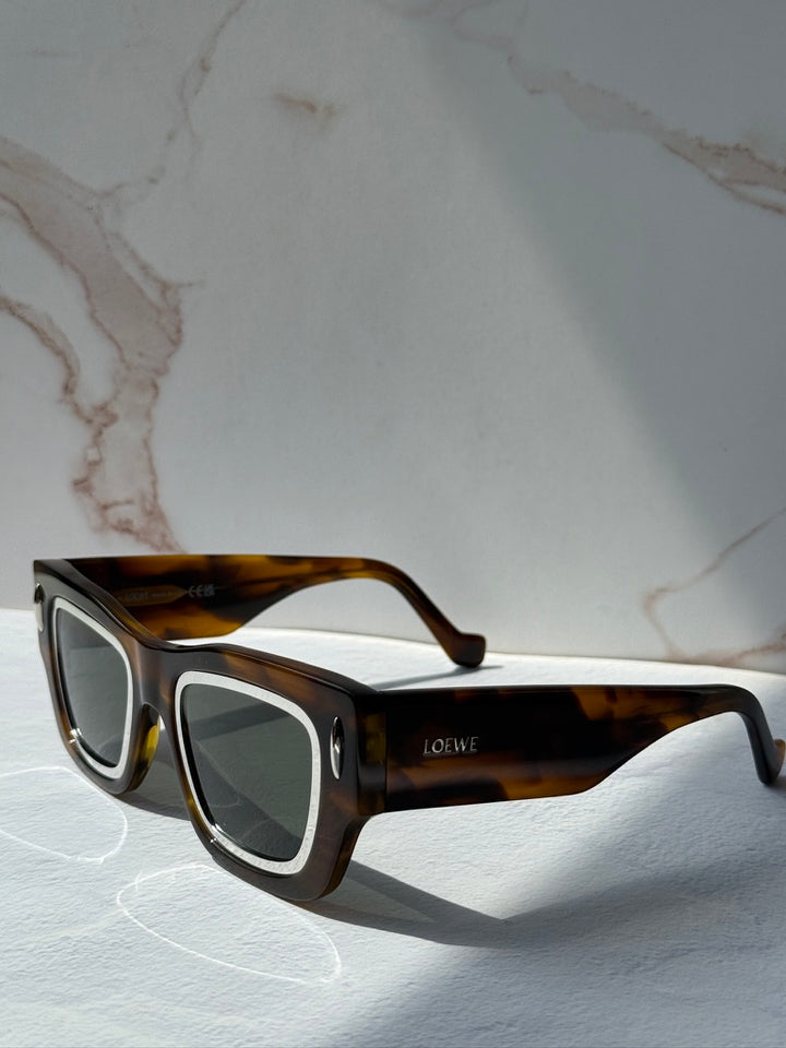 Brown tortoiseshell square sunglasses with pale trim around the dark lenses