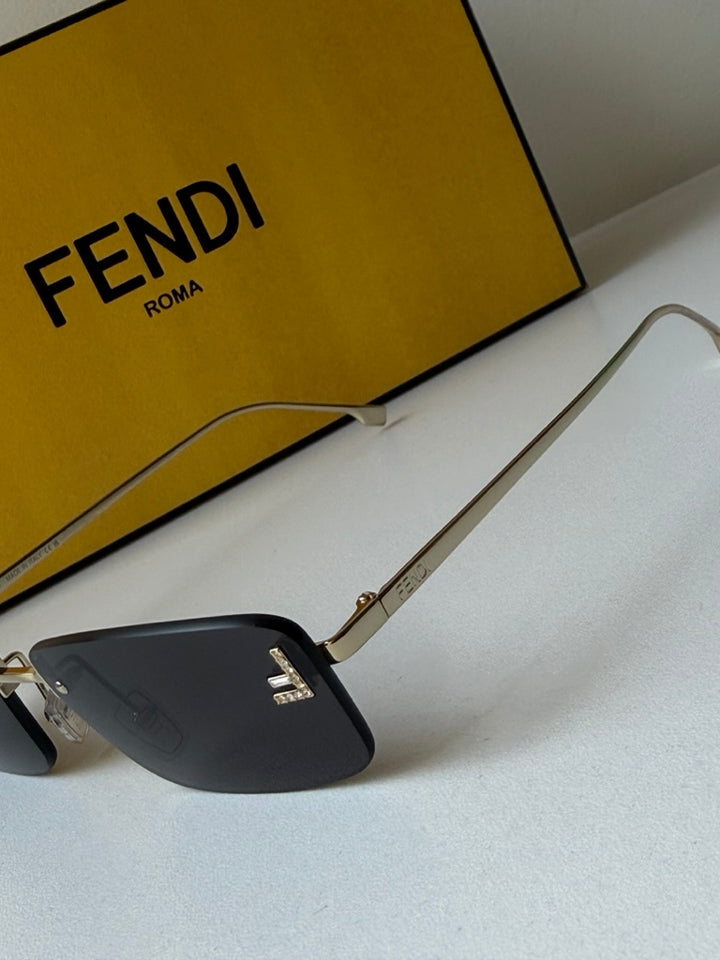 Rimless sunglasses with dark lenses and gold metal frame, branded temple accents