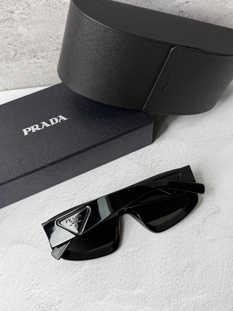 Black PRADA sunglasses, close-up of angular frame and dark shield lenses