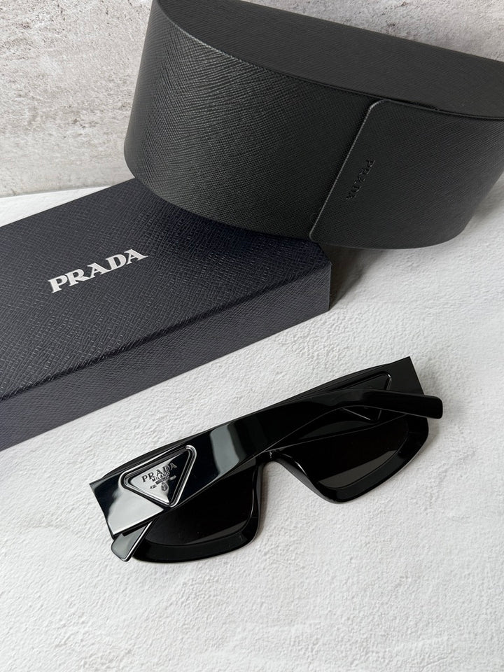 Black PRADA sunglasses, close-up of angular frame and dark shield lenses