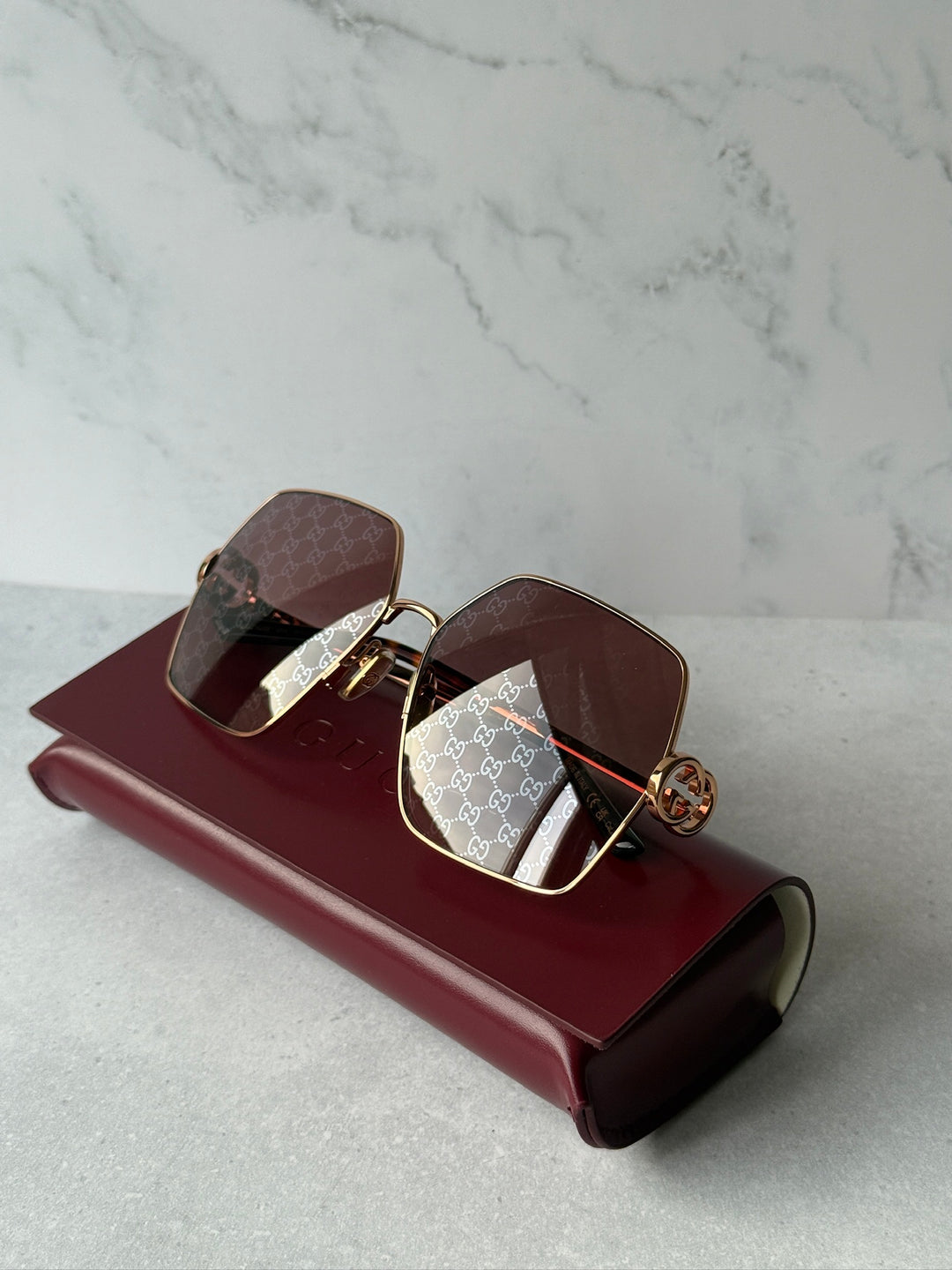 Oversized sunglasses with rose gold metal frame, dark lenses, and logo-embossed temples