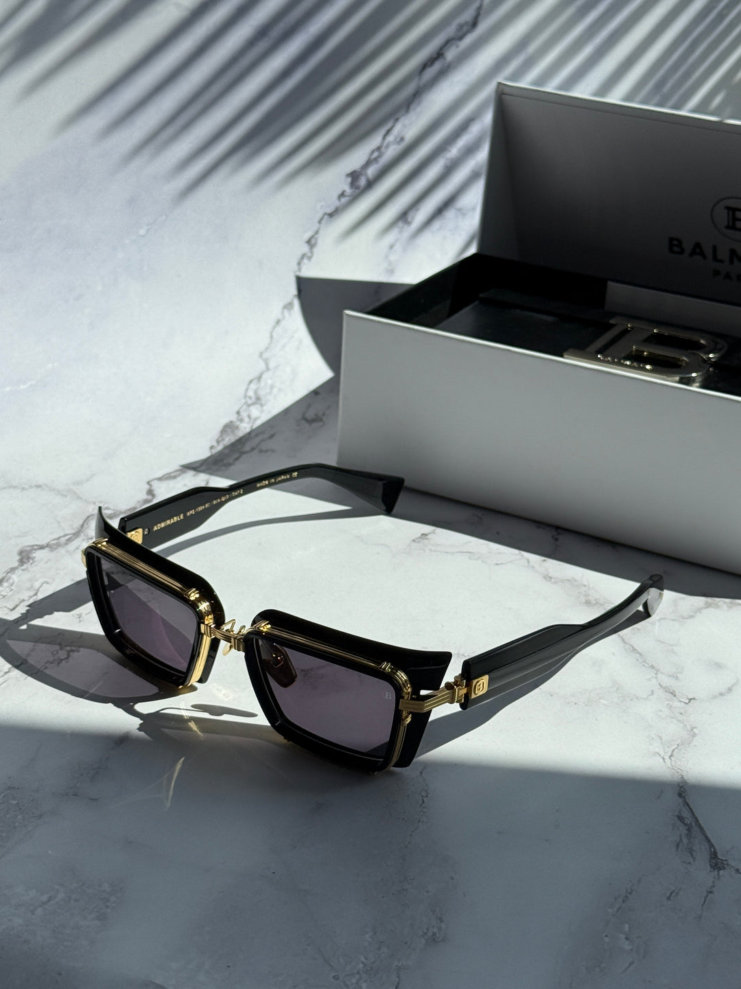 Balmain black square sunglasses with gold detailing next to Balmain case