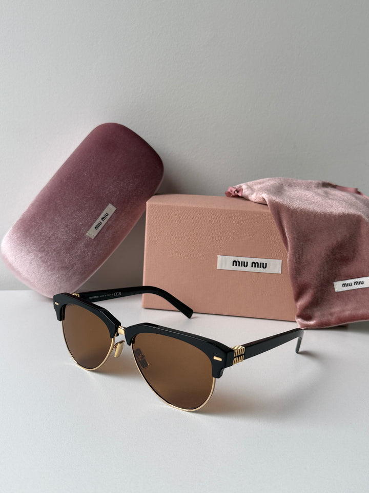 Miu Miu black cat-eye sunglasses with brown lenses beside dust bag and pink cloth