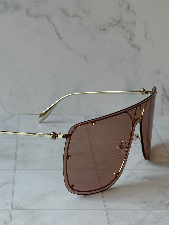 Oversized nude shield sunglasses showing gold temple and brown tinted lens
