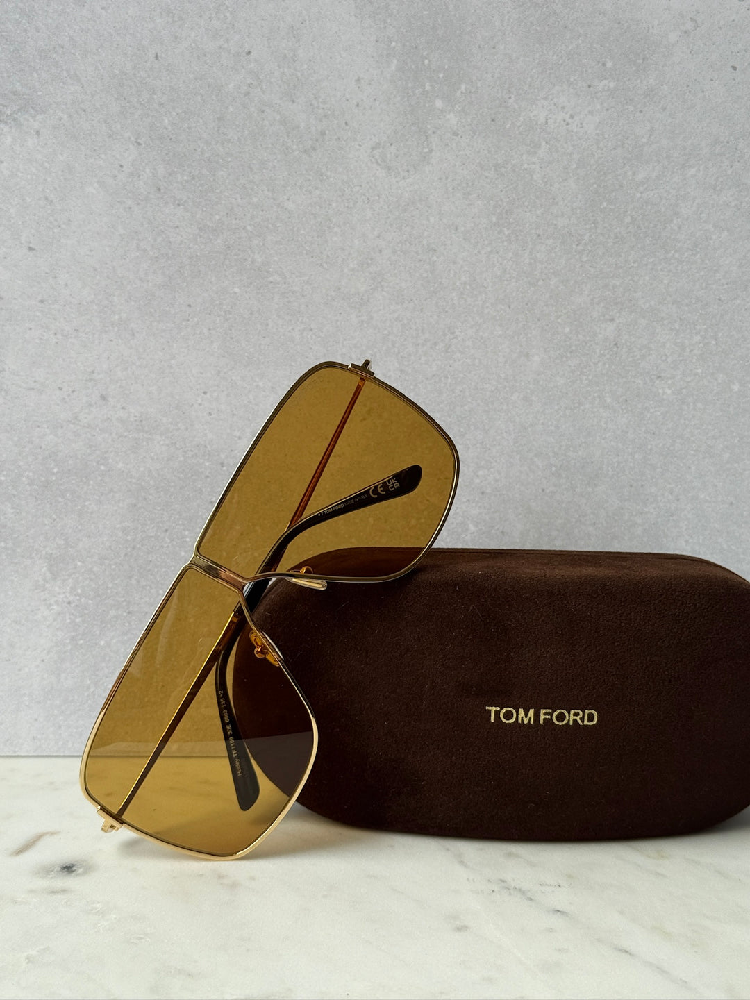 Gold square aviator sunglasses with amber lenses, shown with brown protective case