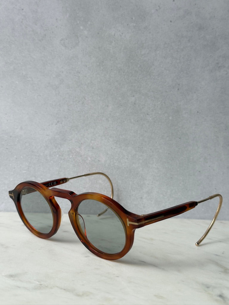 Brown tortoise round sunglasses in three-quarter view with gold-tone metal temples