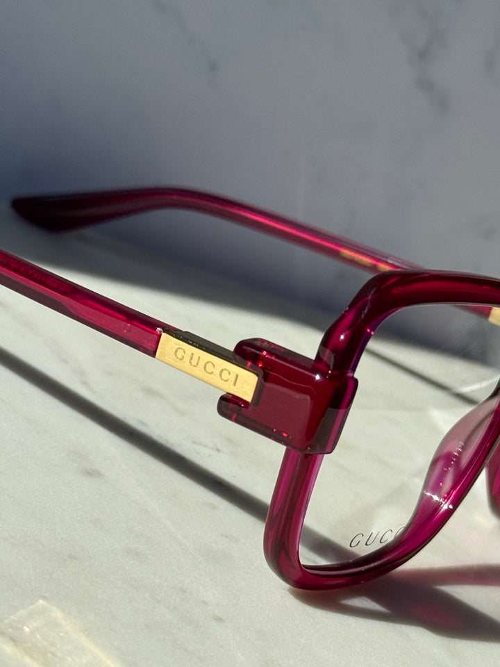 Close-up of pink red oversized square eyeglasses temple with Gucci logo