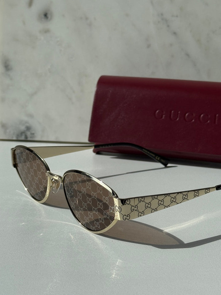 Gucci cat-eye sunglasses angled view, gold-tone frame and GG monogram brown lenses