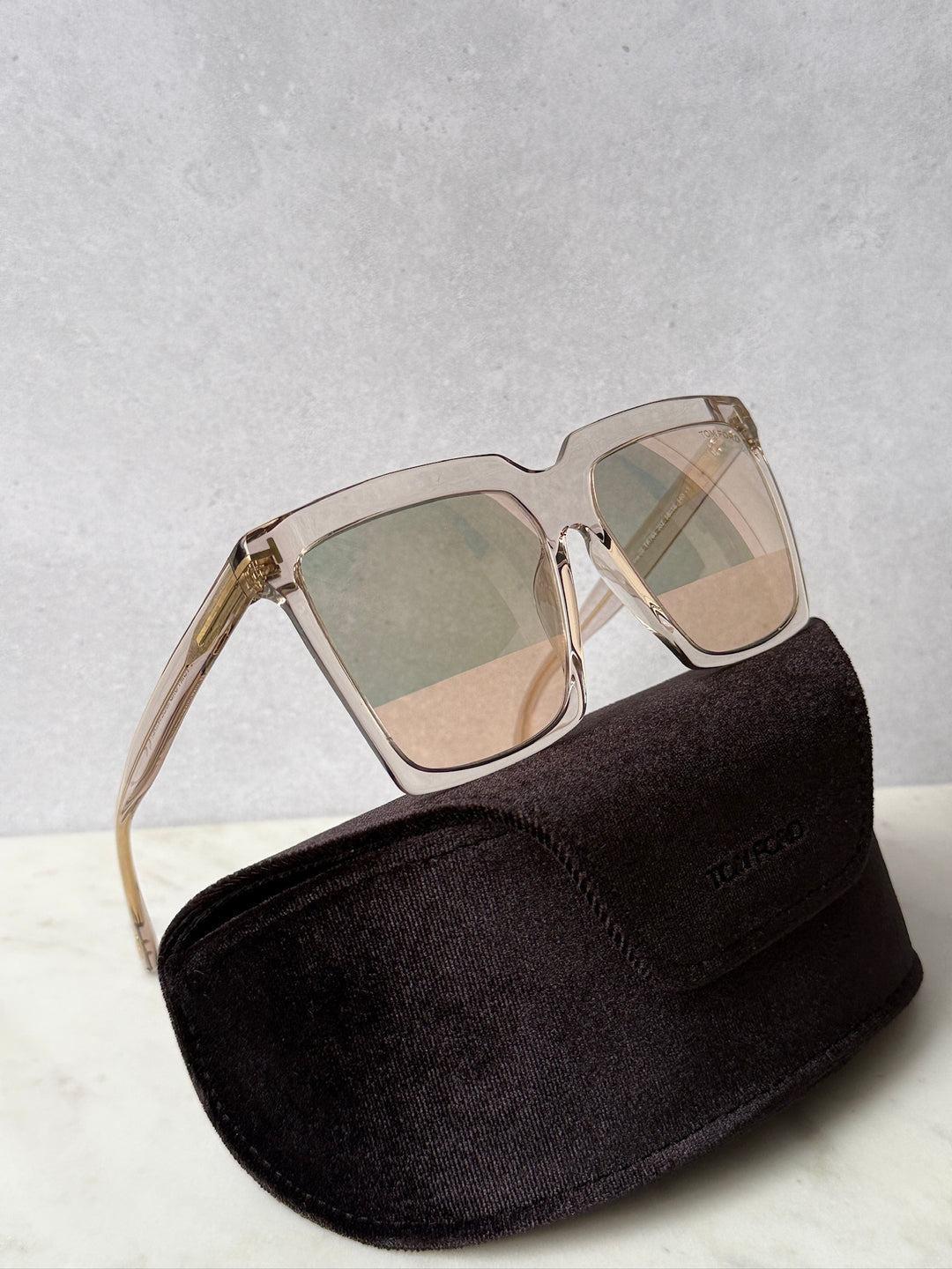 Square transparent mirror sunglasses with gold-tone frame on black case